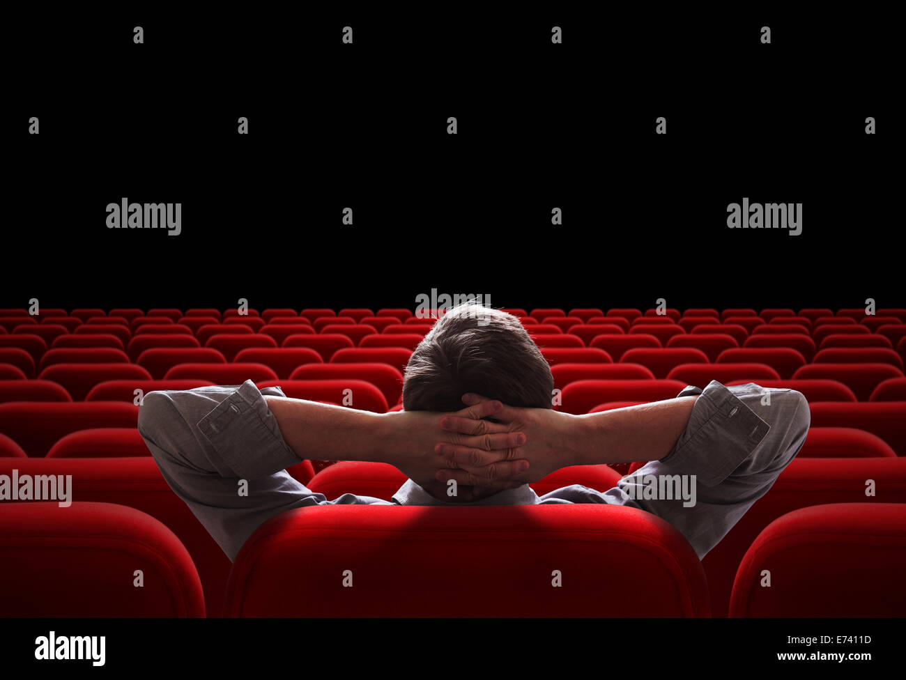 one man sitting in empty cinema or theater auditorium Stock Photo