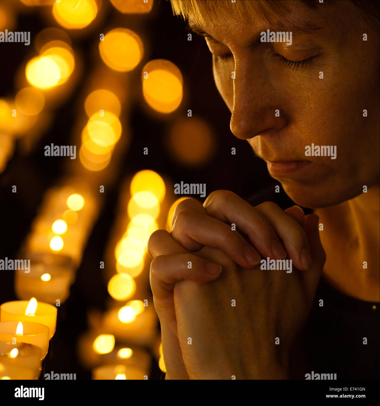 Prayer praying in Catholic church near candles. Religion concept. Stock Photo