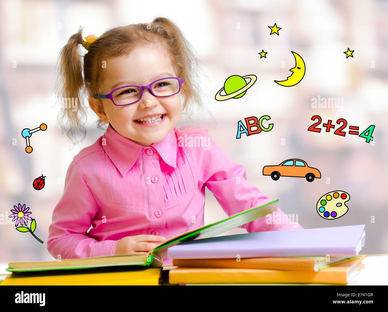 Happy child girl in glasses reading books in library Stock Photo