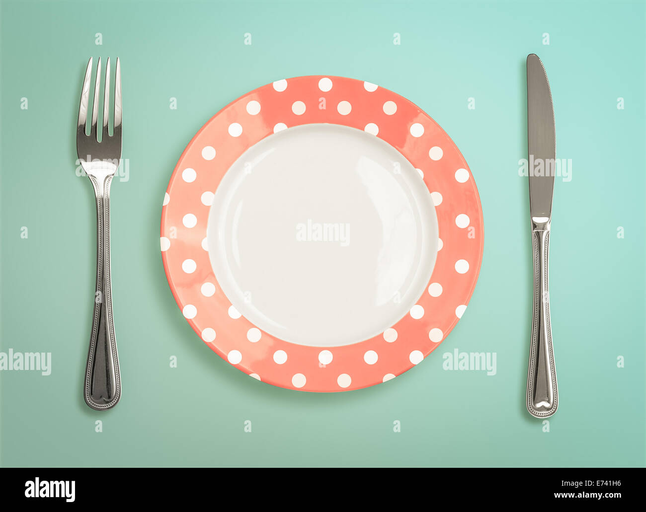 Retro polka dot plate with fork and knife top view Stock Photo