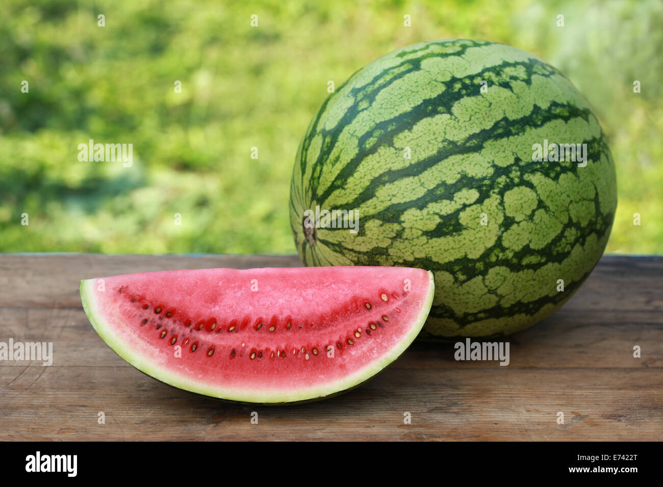 Slice of a watermelon and a whole one on a wooden table Stock Photo
