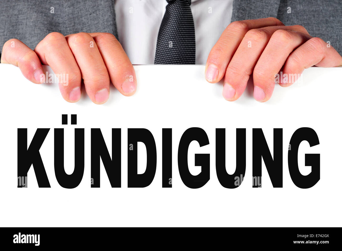 a businessman showing a signboard with the word kundigung, dismissal in german, written in it Stock Photo