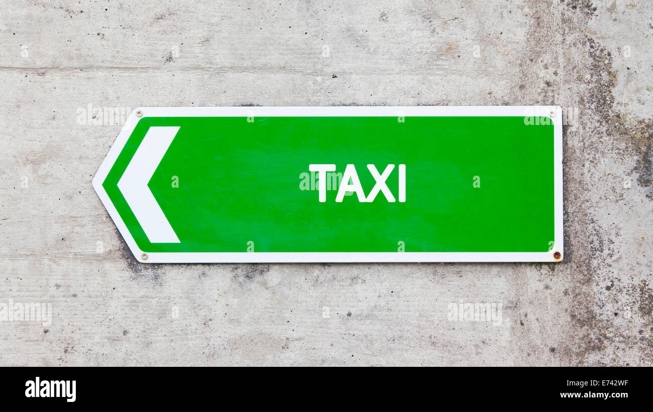 Green sign on a concrete wall - Taxi Stock Photo