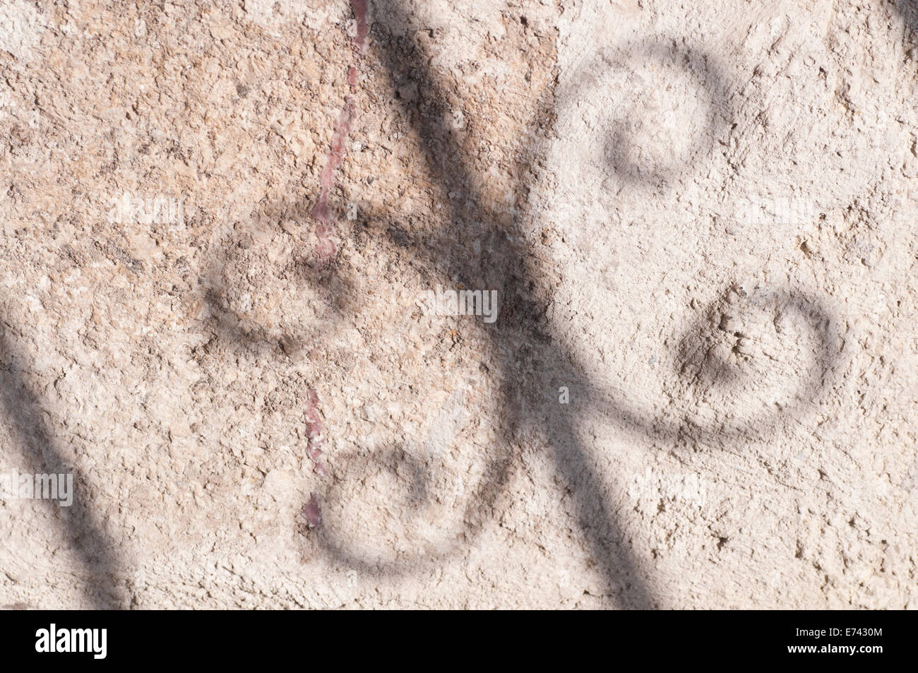 A shadow from a wrought iron staircase against a grey plastered wall Stock Photo