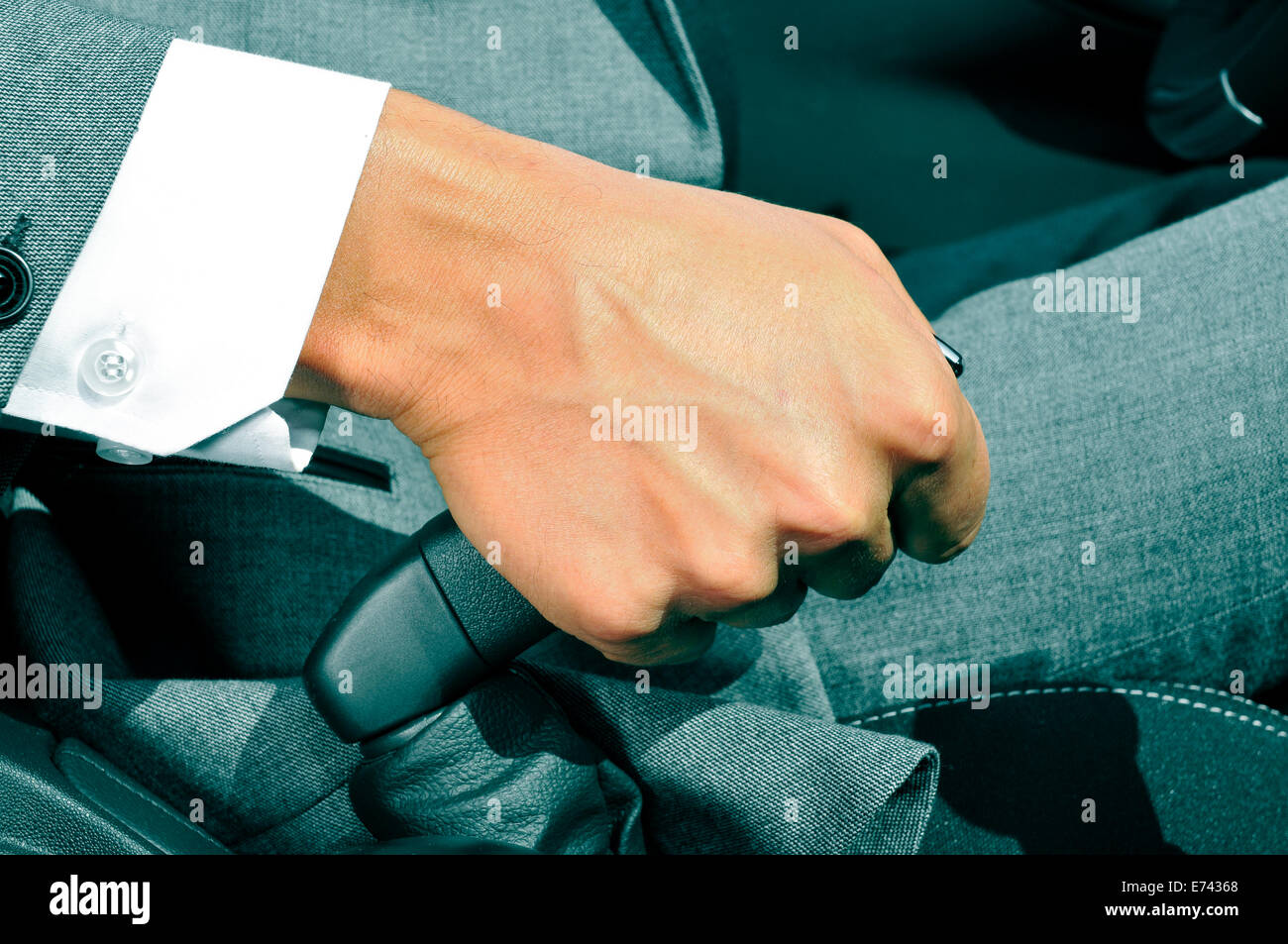 closeup of a man in suit pulling the hand brake of a car Stock Photo
