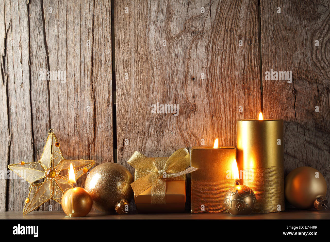 Grunge wood background with burning candles,gold balls and star. Stock Photo
