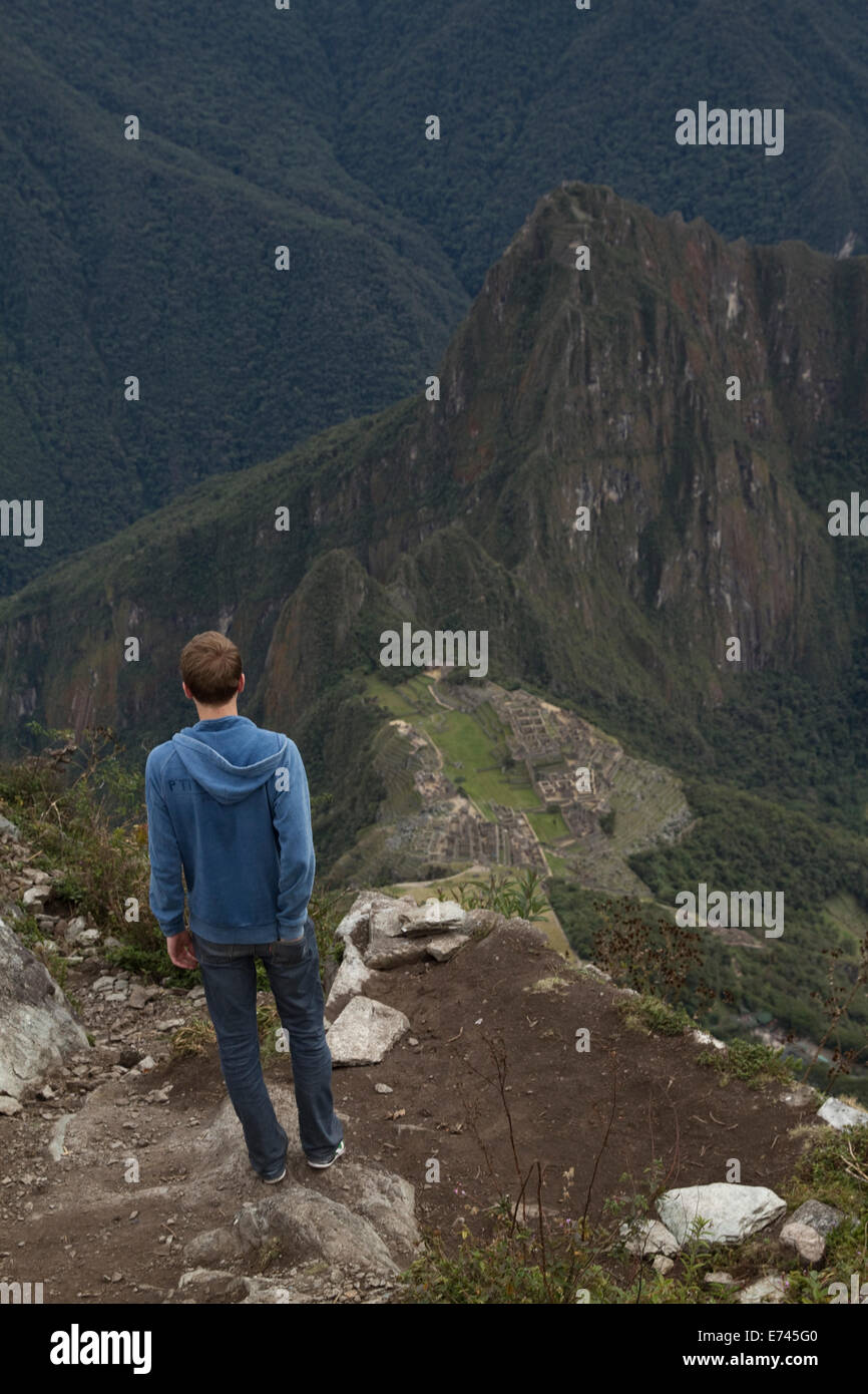 A tourist enjoys the amazing view of Machu Picchu sanctuary from the peak of Machu Picchu mountain in Peru. Stock Photo