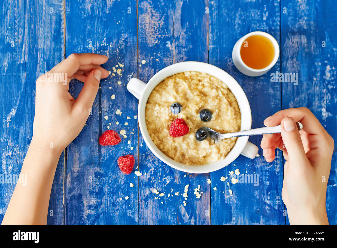 Porridge bowl with berries and honey on wooden table Stock Photo