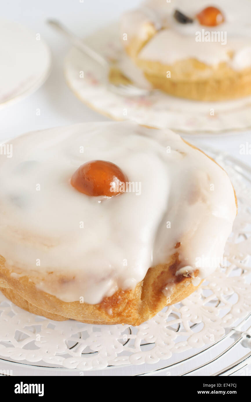 Belgian bun a sweet bun containing sultanas and topped with fondant icing Stock Photo