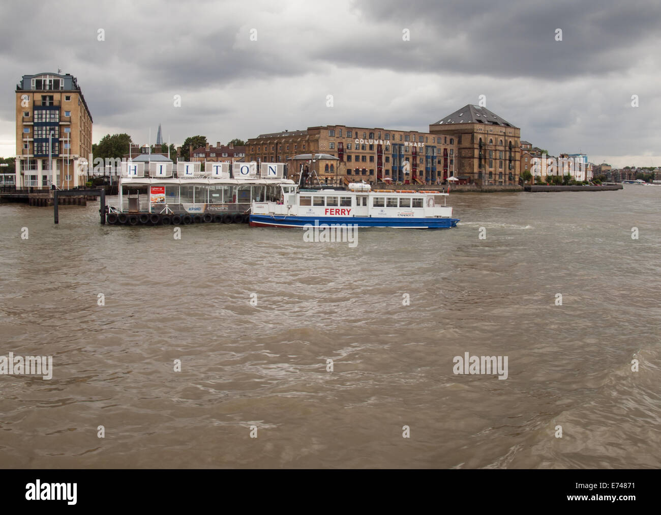 the hilton pier with ferry boat, hilton docklands and the columbia wharf building london rotherhithe Stock Photo