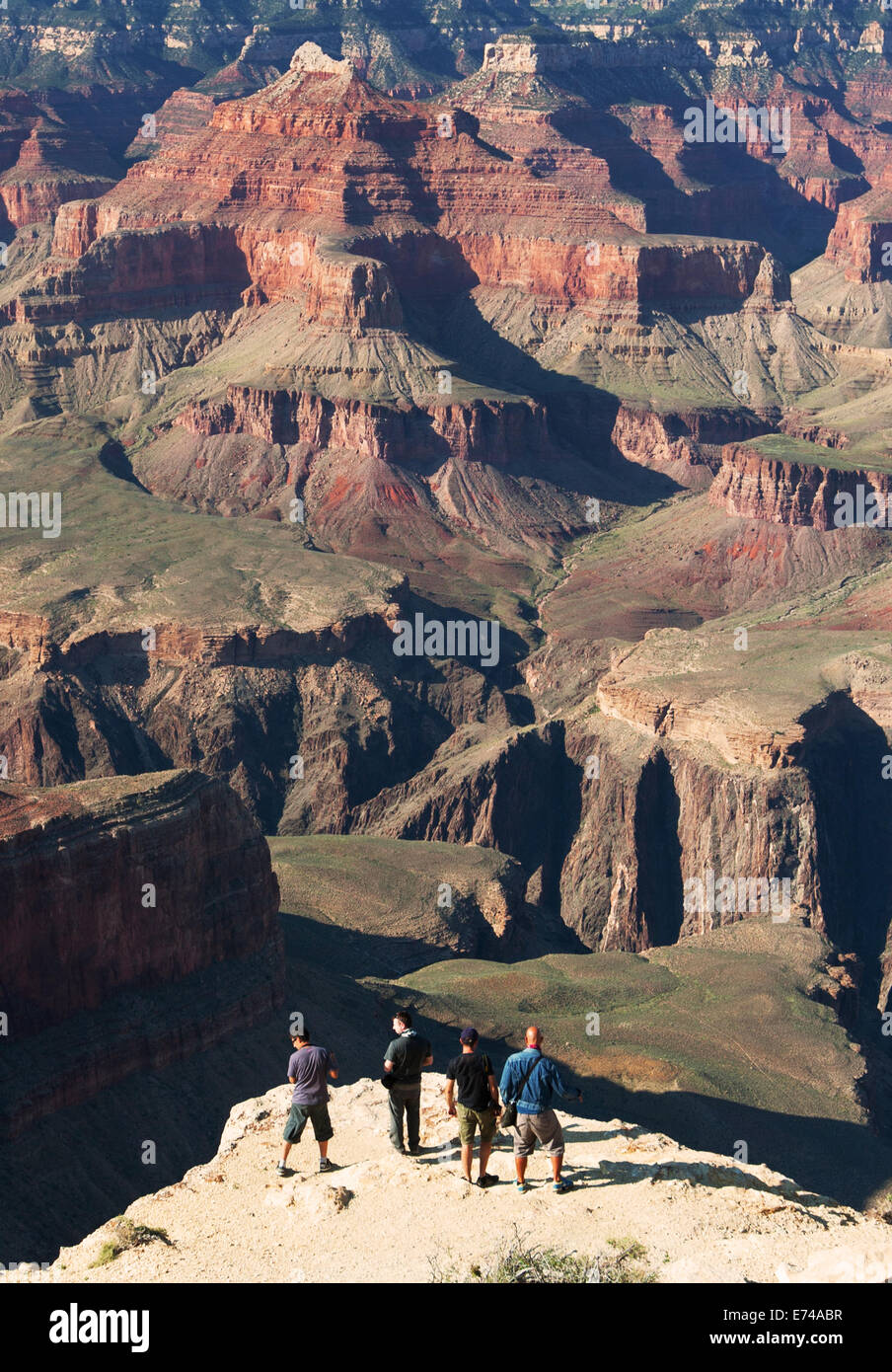 Men standing on edge of rock precipice overlooking Grand Canyon. Stock Photo