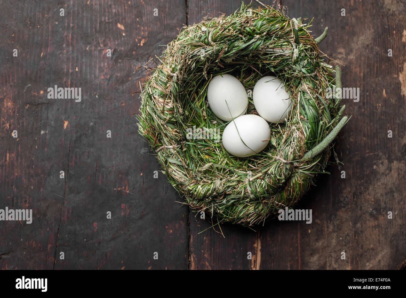 Organic white eggs in hay nest at wooden table. Eco food composition in rural vintage style Stock Photo
