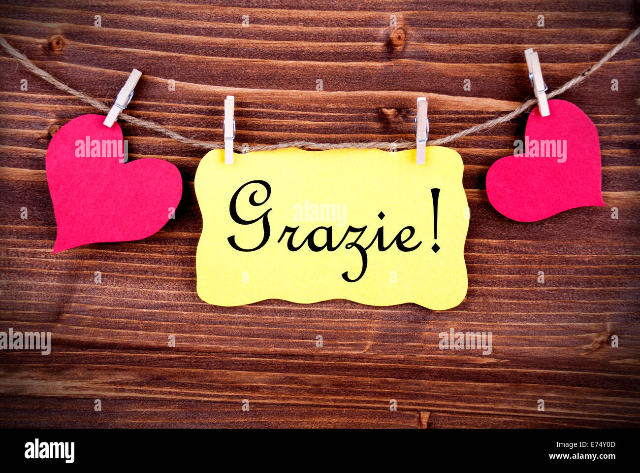 The Italian Word Grazie, which means Thanks, on a Yellow Label, framed by  two red Hearts on a Line on wooden Background Stock Photo - Alamy