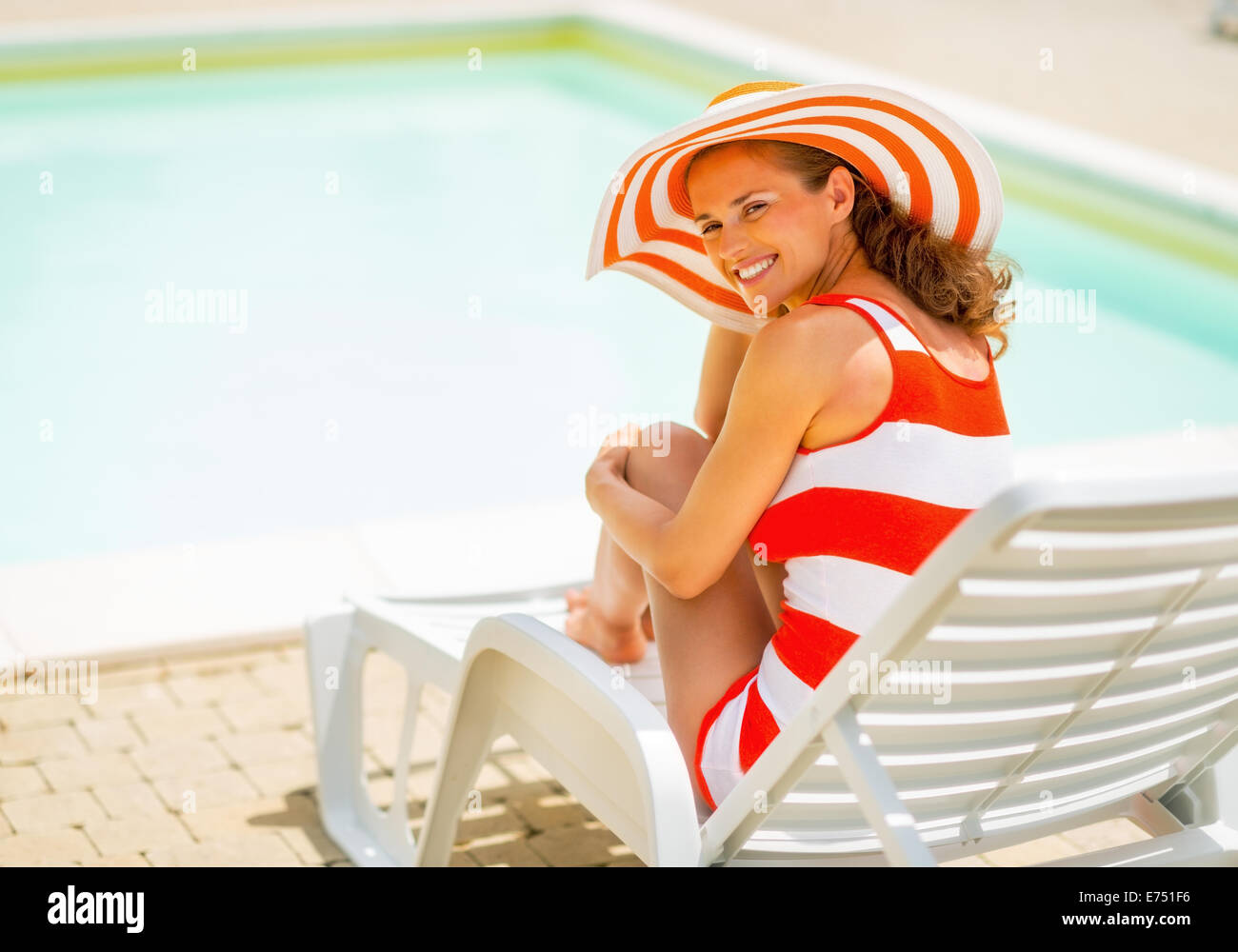 Happy young woman in hat sitting on sunbed Stock Photo - Alamy