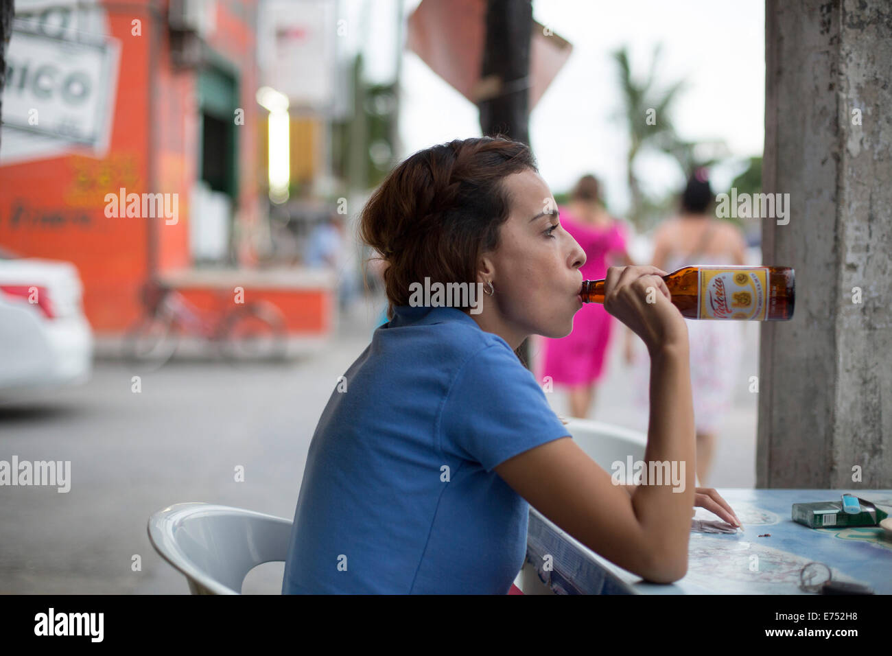 woman drinking bottle beer from neck outside bar Stock Photo