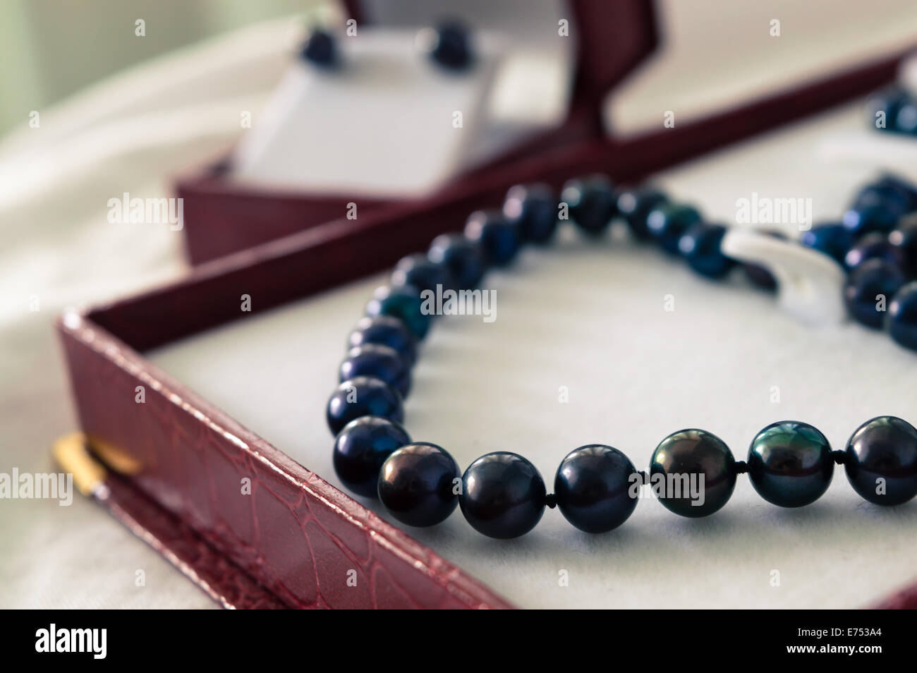 A black pearl necklace in a red jewelry box Stock Photo