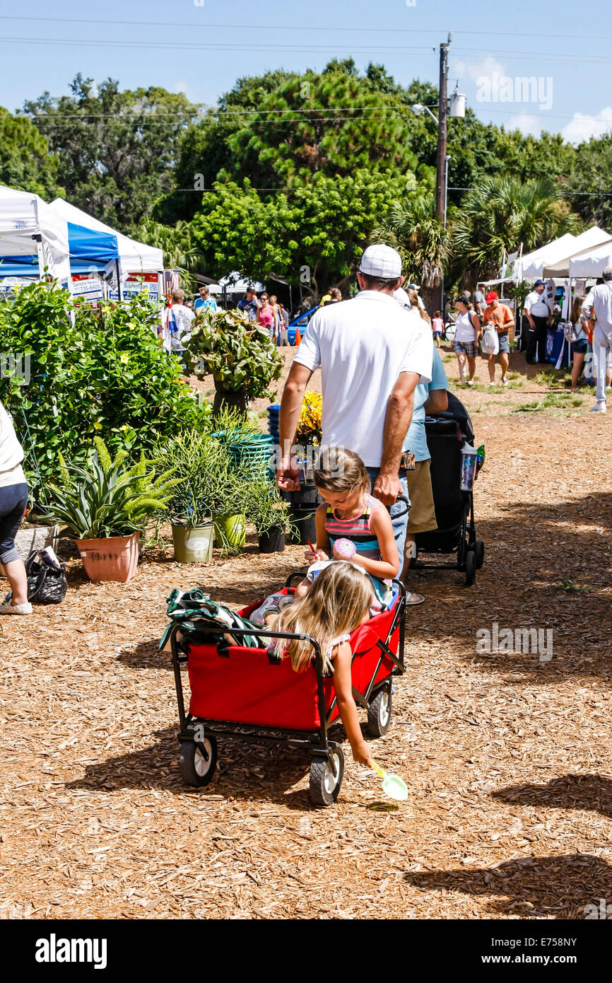 Children being pulled around a farmers market in little red wagon Stock Photo