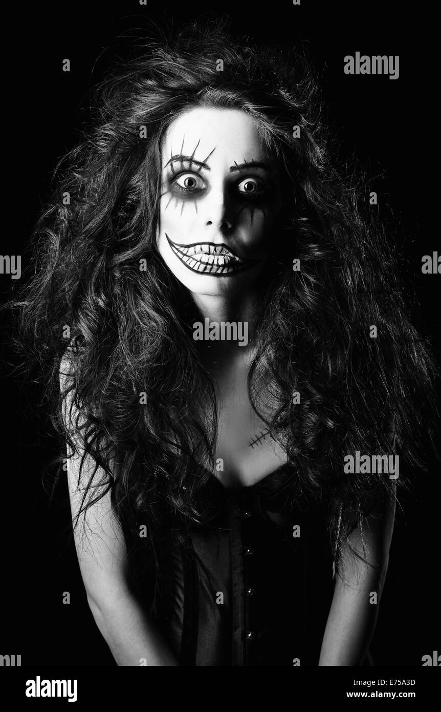 Beautiful young woman in the image of a sad gothic freak clown. Black and white Stock Photo