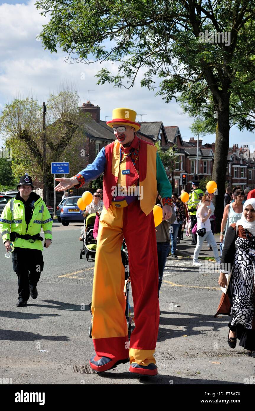 Gorton, Manchester, UK. 7th Sep, 2014. Gorton Carnival Parade on way to Debdale Park, with a stop on Tesco car park, Gorton, for several of the groups in the parade to perform for spectators.-'Smilie' the clown on stilts walks with the parade Stock Photo