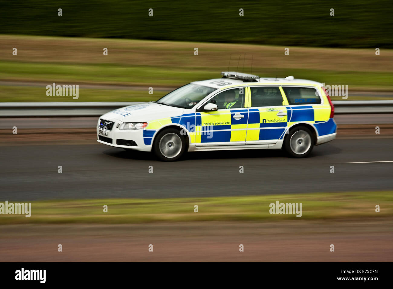 A Police Scotland police car responding at great speed to an emergency 999 call along the Kingsway West Dual Carriageway in urban Dundee, Scotland Stock Photo