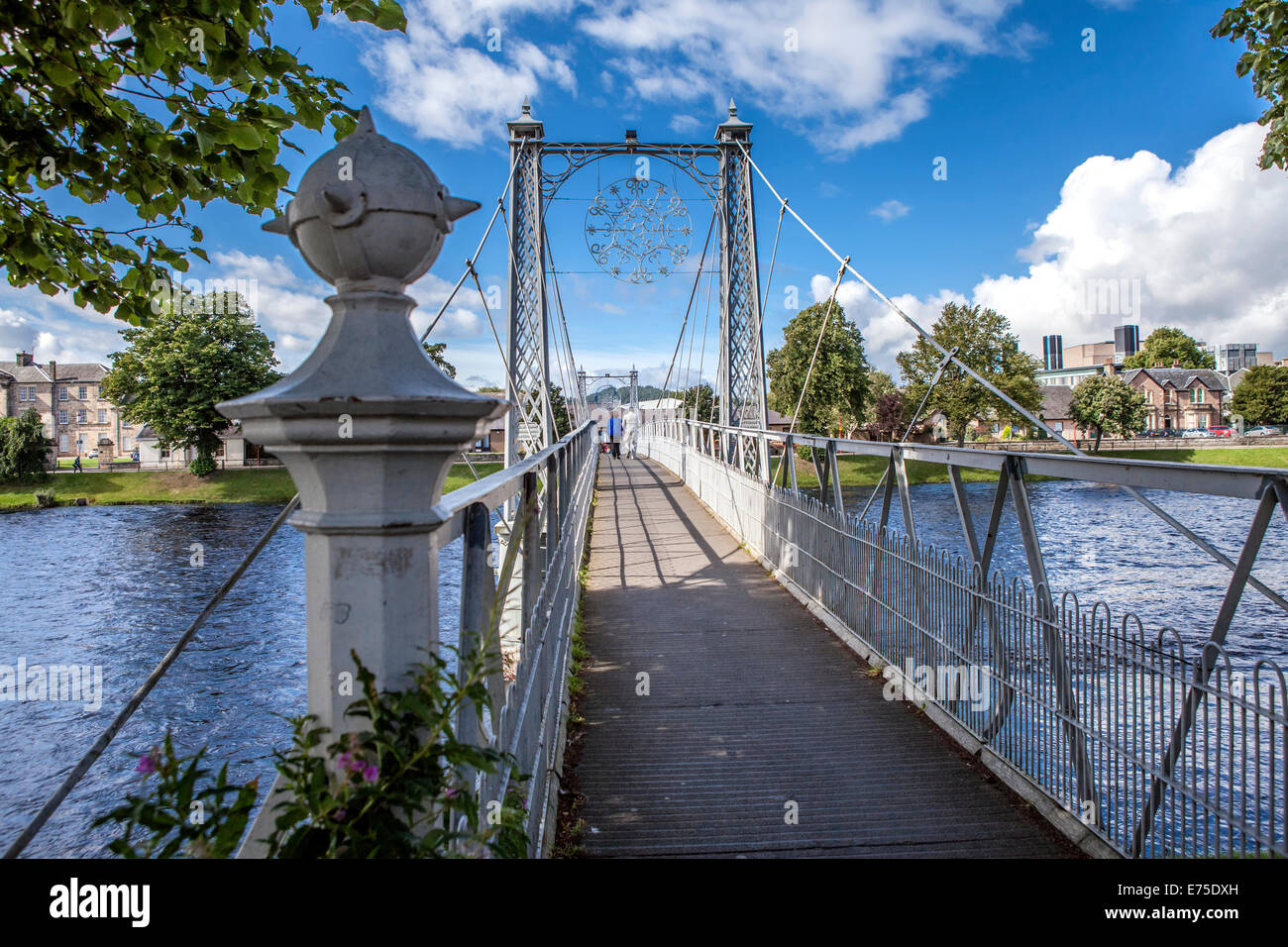 Pedestrian  suspension bridge with two people walking in the back Stock Photo