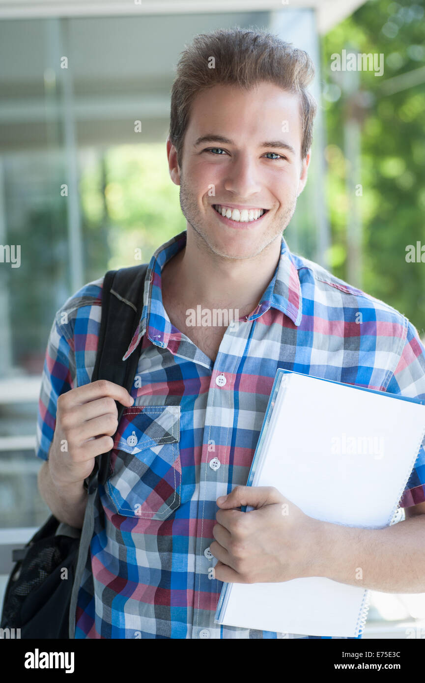Young male wearing backpack and holding folder Stock Photo - Alamy
