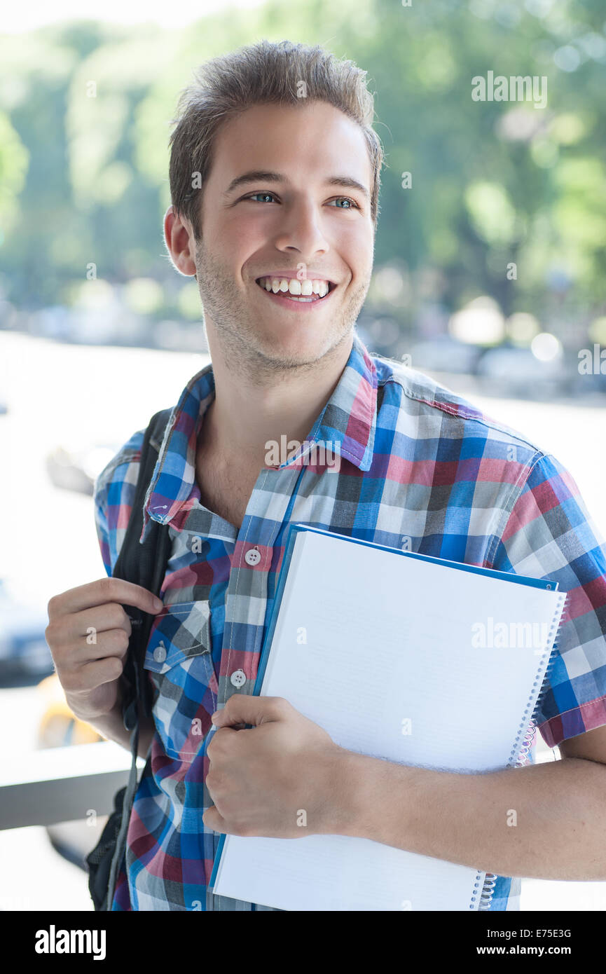Young male wearing backpack and holding folder Stock Photo - Alamy