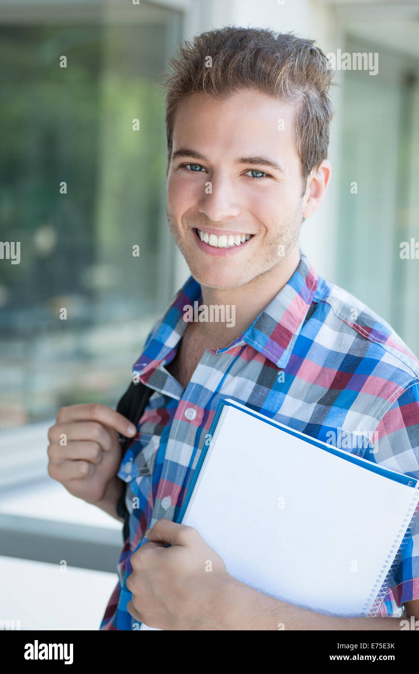 Young male wearing backpack and holding folder Stock Photo - Alamy