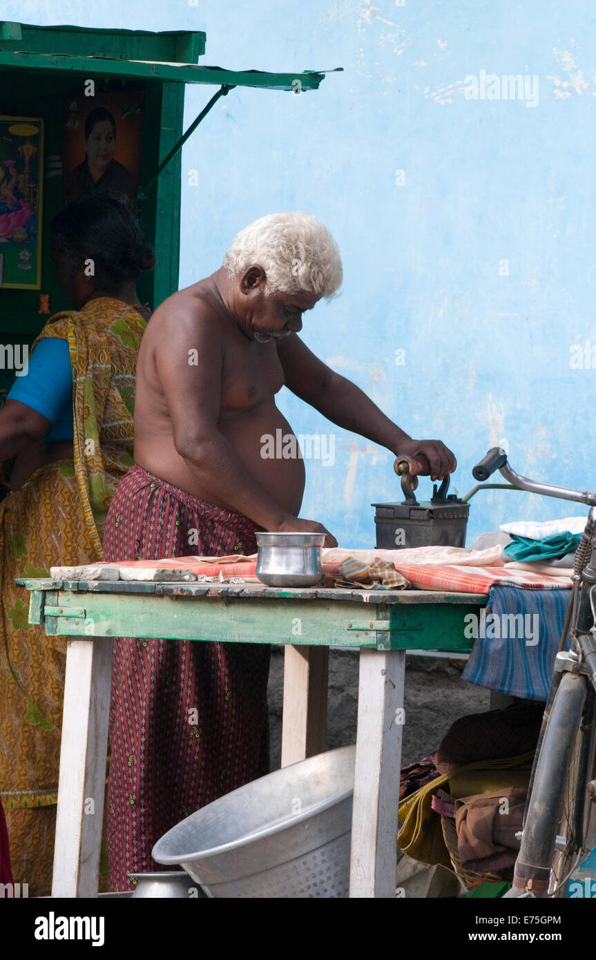 Indian gentleman & wife at work in laundry shop ironing clothes Tiruvannamalai street foot of sacred Arunachala South India Stock Photo