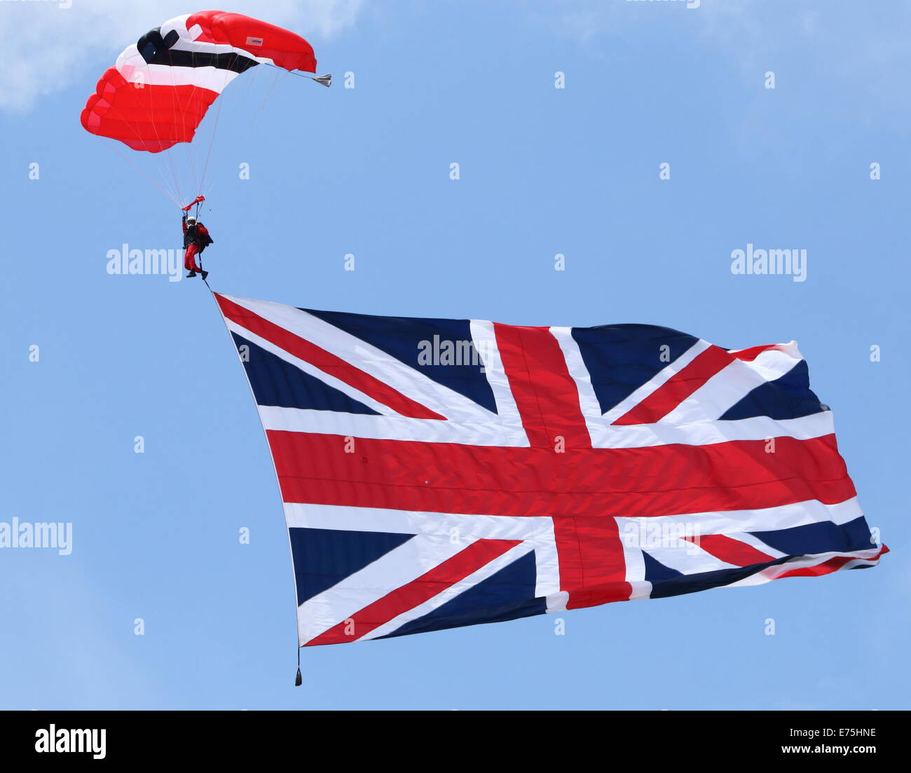 The Parachute Regiment's Red Devils parachute display team display a giant Union Jack flag during a jump in England. Stock Photo