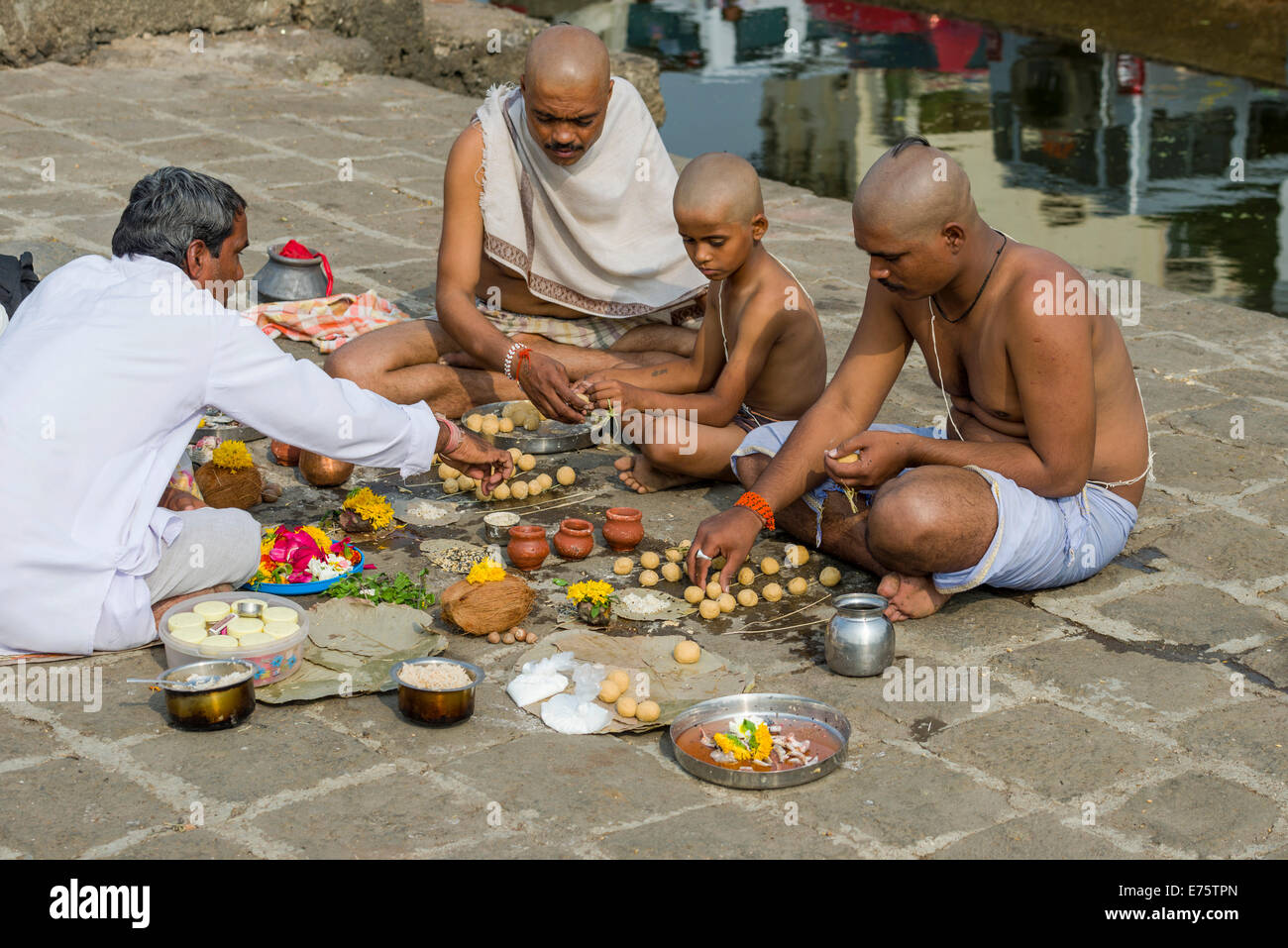 Two men, a boy and a pandit or priest are performing Dashkriya or Asthi Visarjan, a ritual which is performed 10 days after the Stock Photo