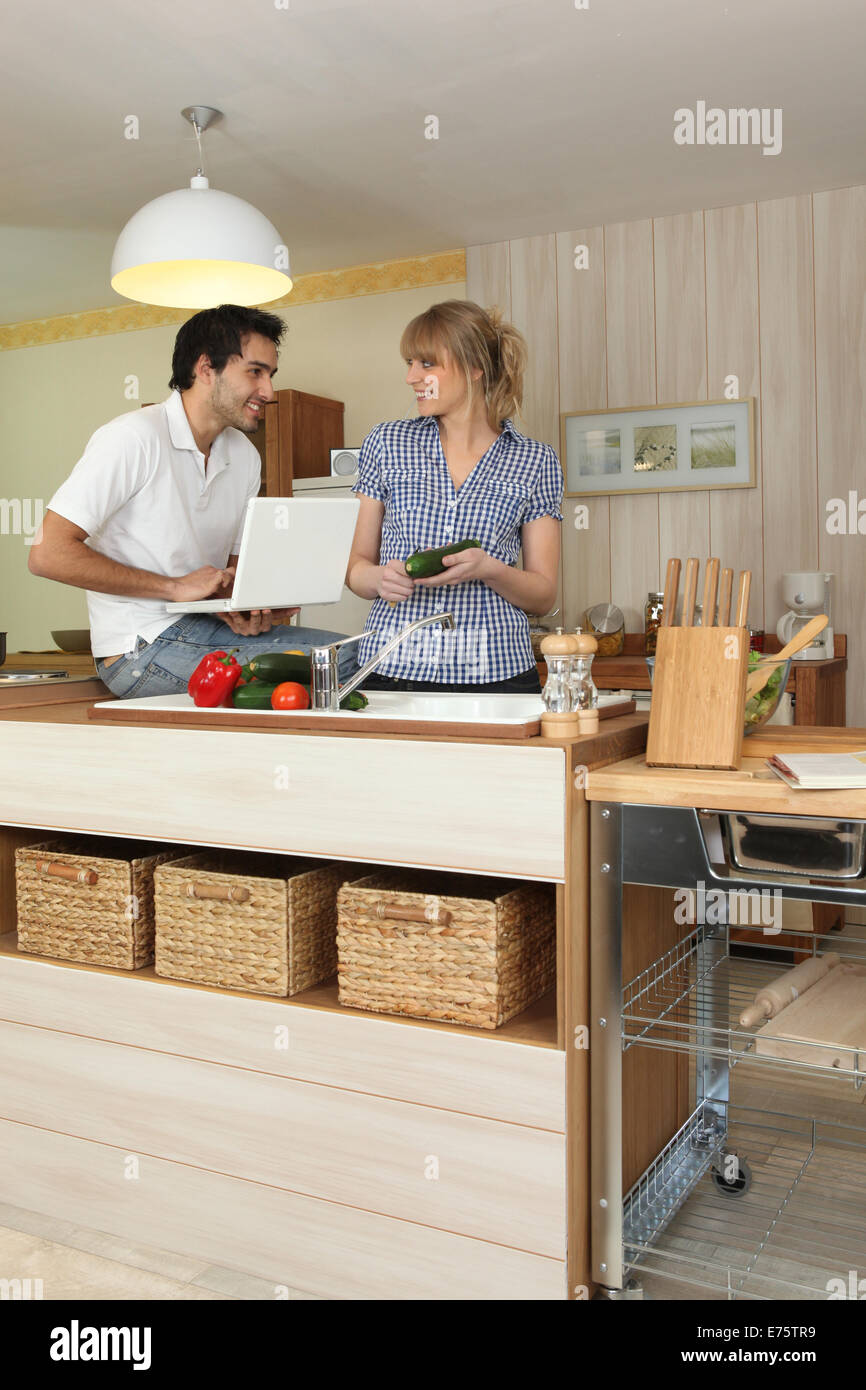 Young man and young woman smiling in kitchen Stock Photo - Alamy