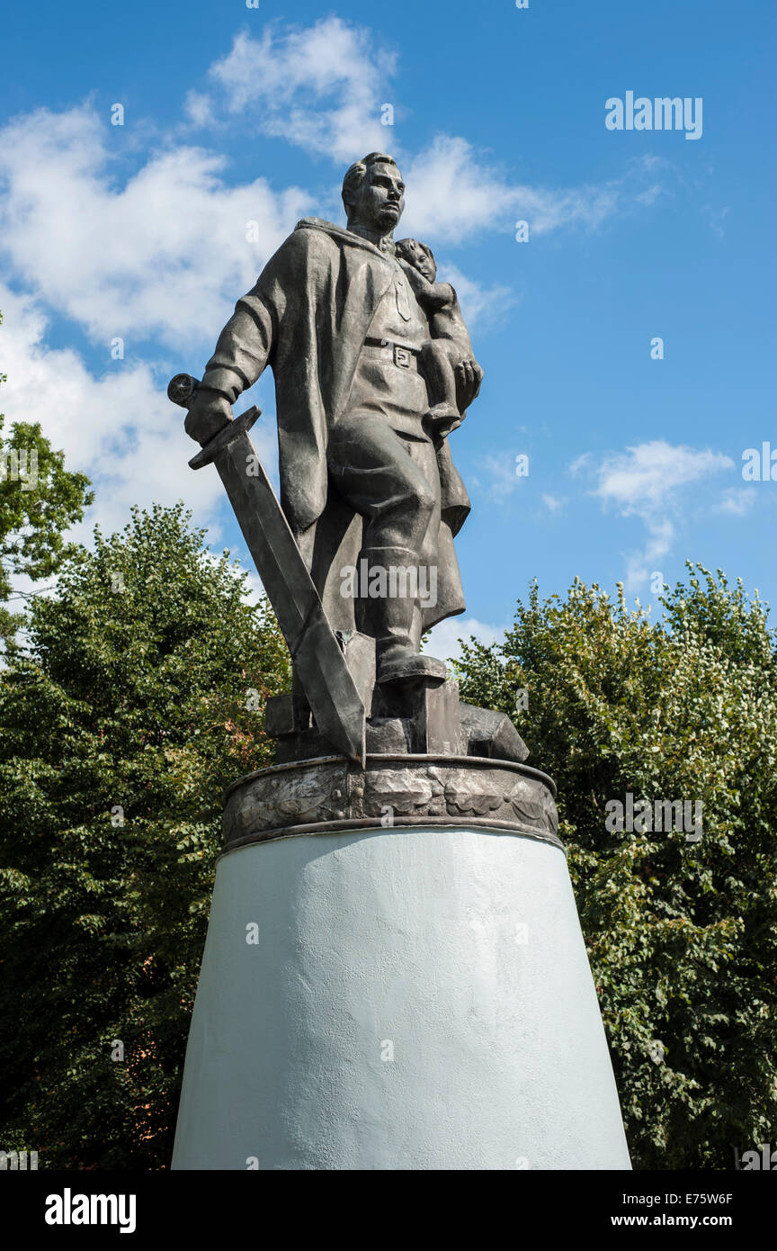 World War II memorial, soldier with big sword in a heroic pose, holding a child, bronze sculpture on a pedestal, Tilsit, Sovetsk Stock Photo