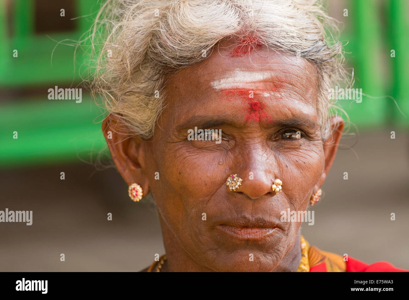Elderly local woman with a bindi on her forehead wearing gold jewelry, inside a Hindu temple, Tiruchirappalli or Trichy Stock Photo