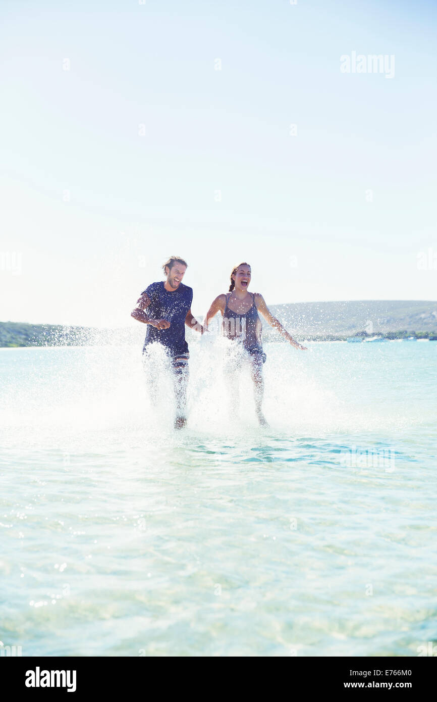 Couple splashing in water on beach Stock Photo