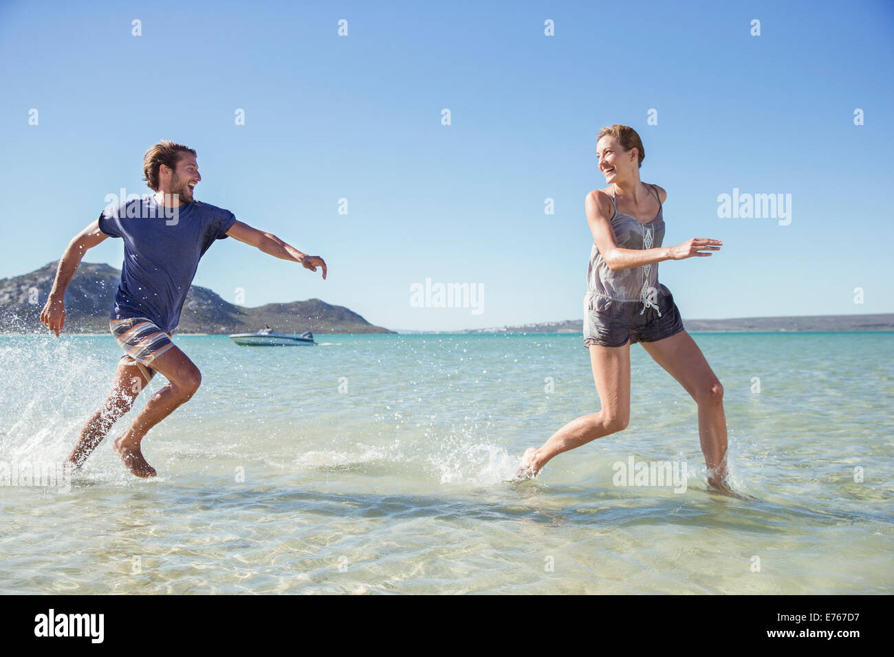 Couple running in waves on beach Stock Photo