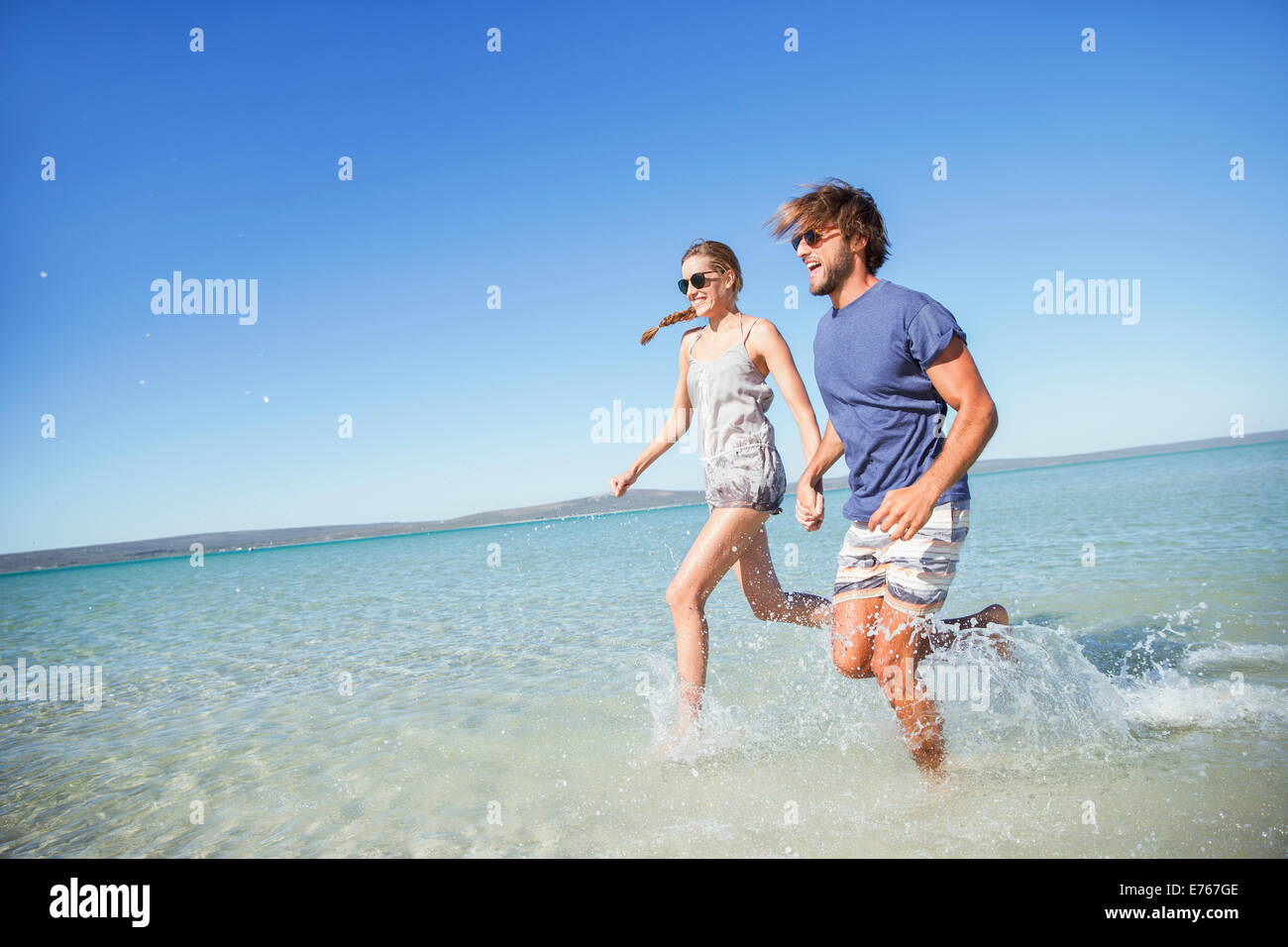 Couple running in water together Stock Photo
