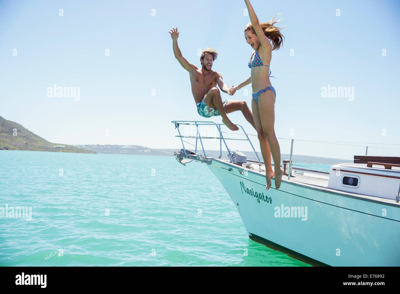Couple jumping off boat together Stock Photo