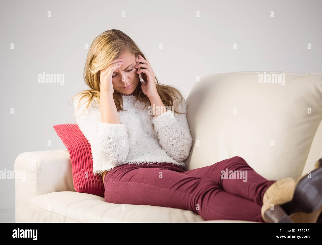 Pretty blonde getting a headache on the couch Stock Photo Alamy