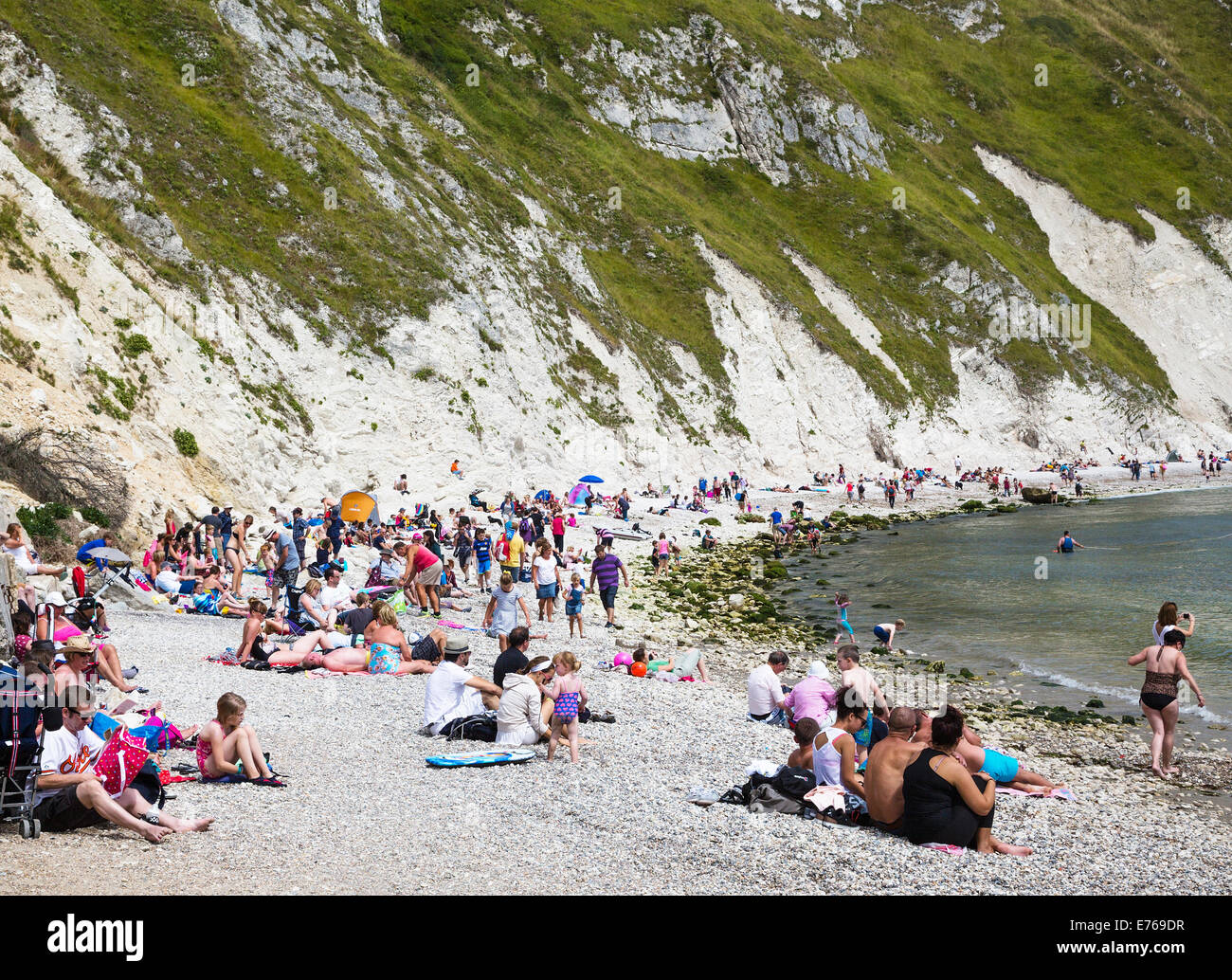 Families enjoying the sunshine on Lulworth Cove beach, Dorset, UK. Stock Photo