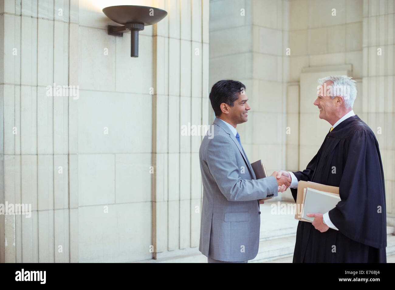 Judge and lawyer shaking hands in courthouse Stock Photo
