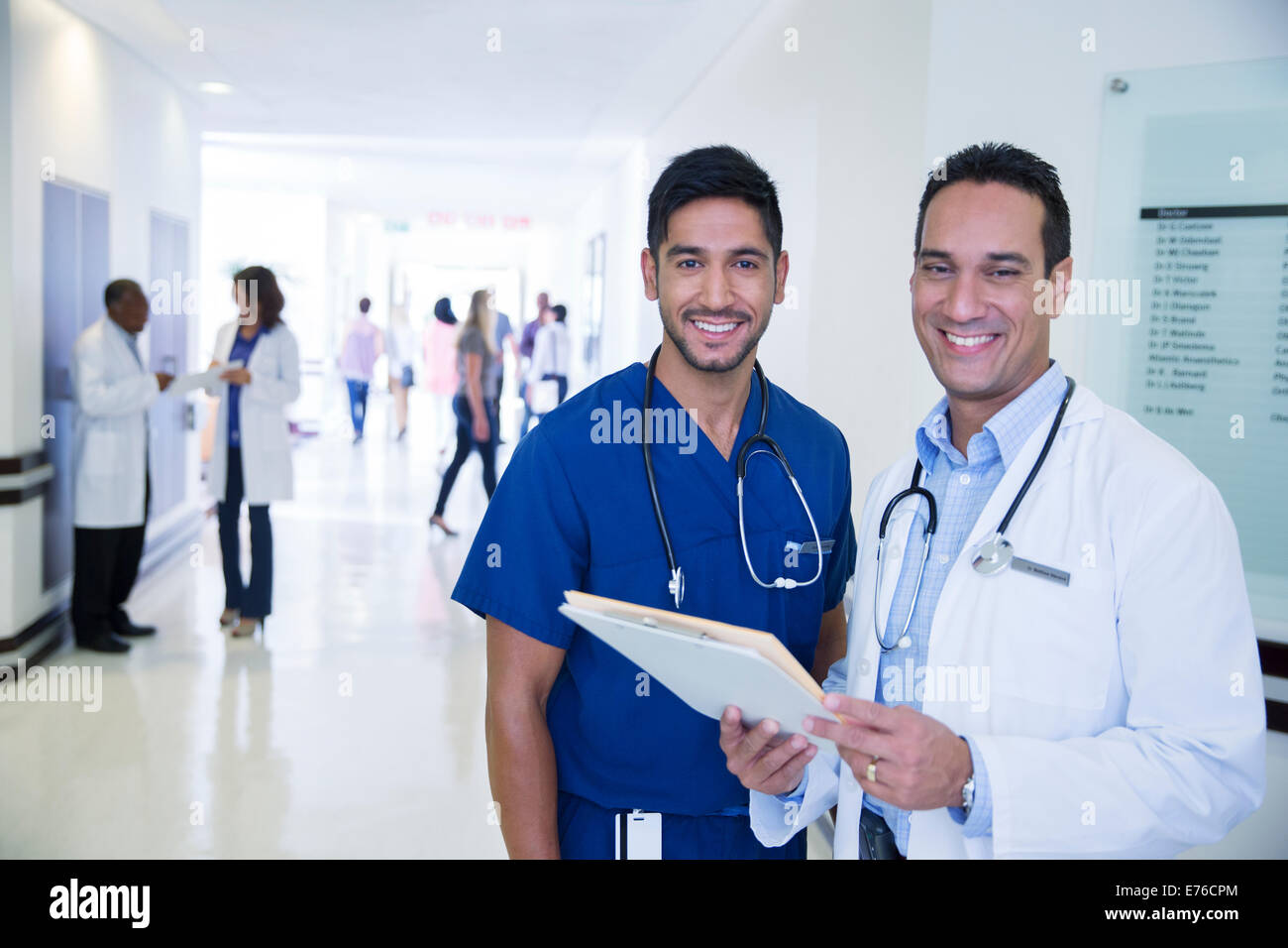 Doctor and nurse smiling in hospital hallway Stock Photo