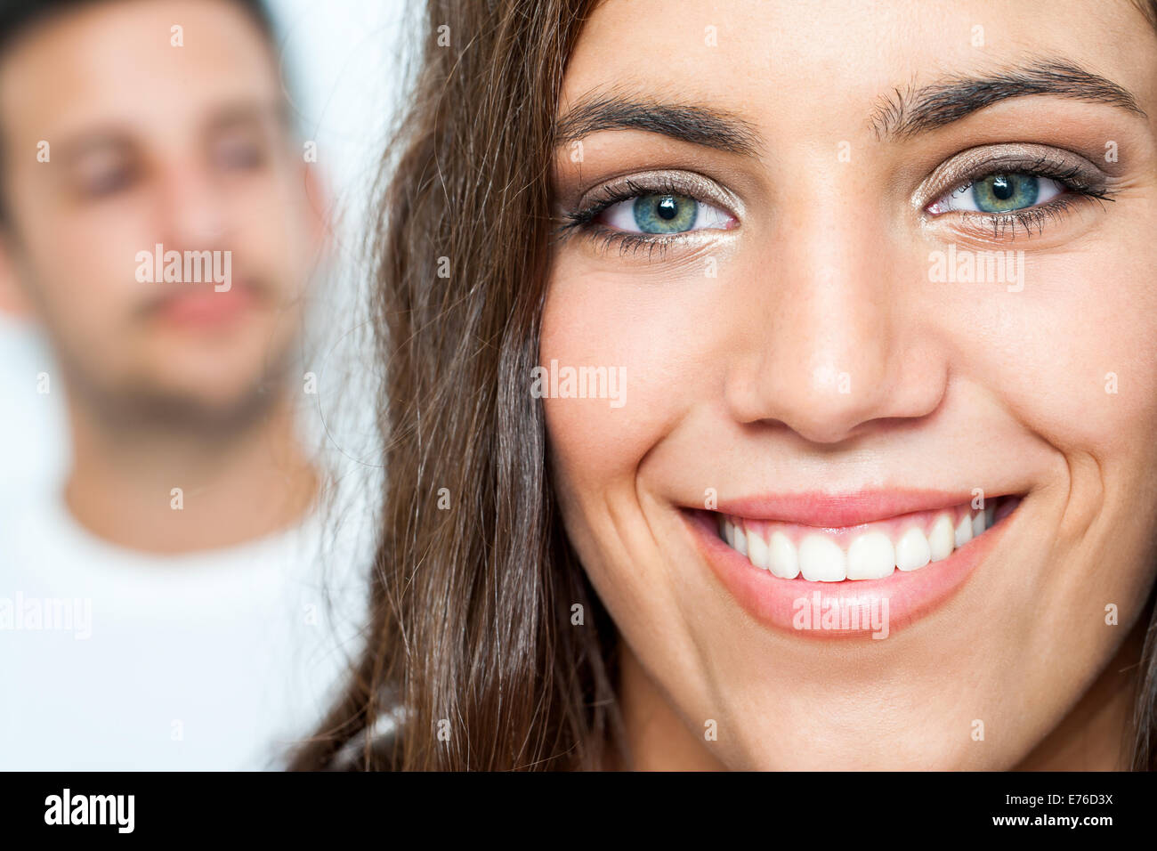 Close up Facial portrait of attractive girl with toothy smile and boy in background. Stock Photo