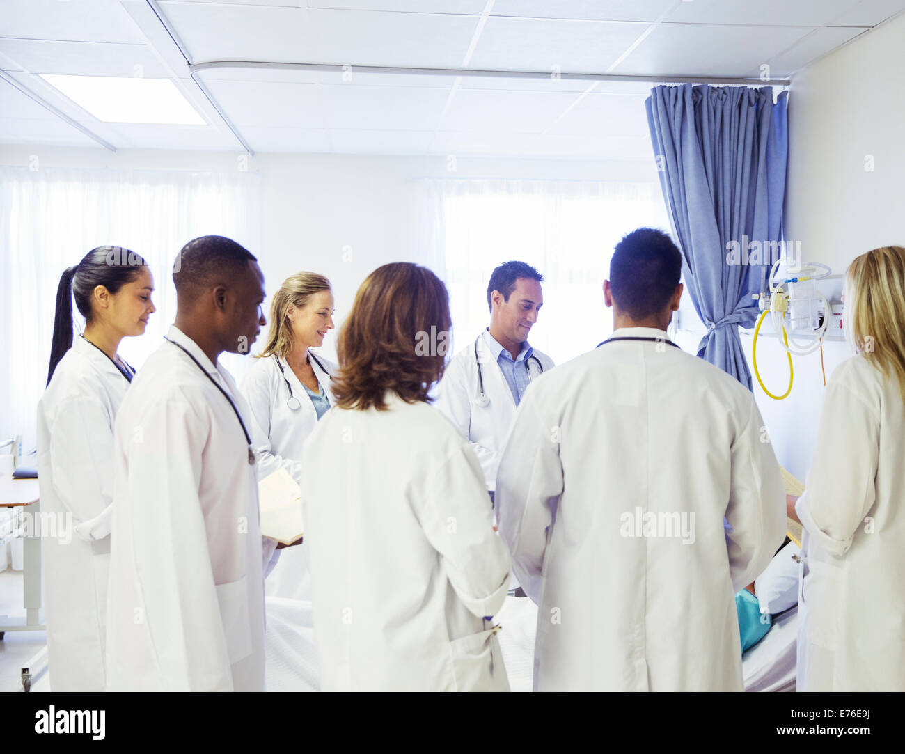 Doctor and residents examining patient in hospital Stock Photo