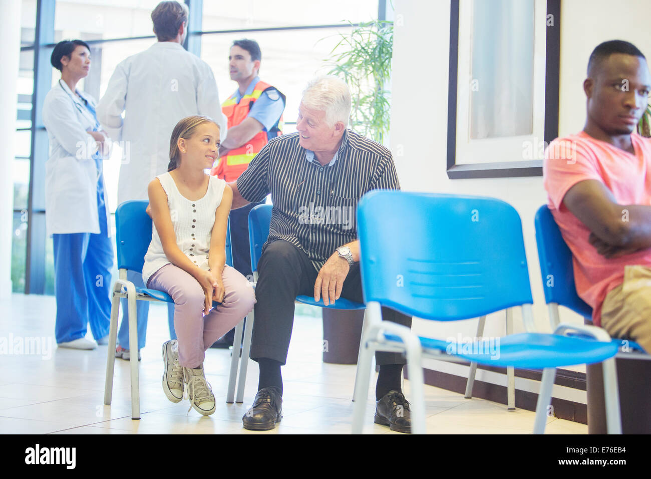 Man and granddaughter sitting in hospital waiting room Stock Photo