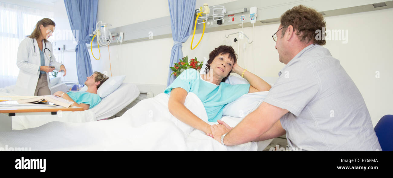 Man talking to wife in hospital room Stock Photo