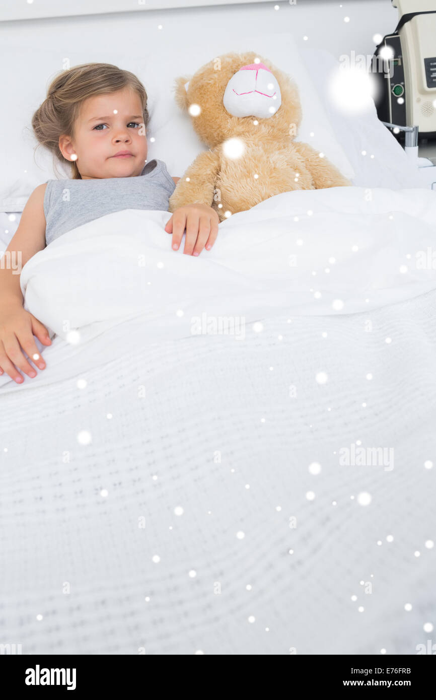 Composite image of girl with teddy bear lying in hospital bed Stock Photo