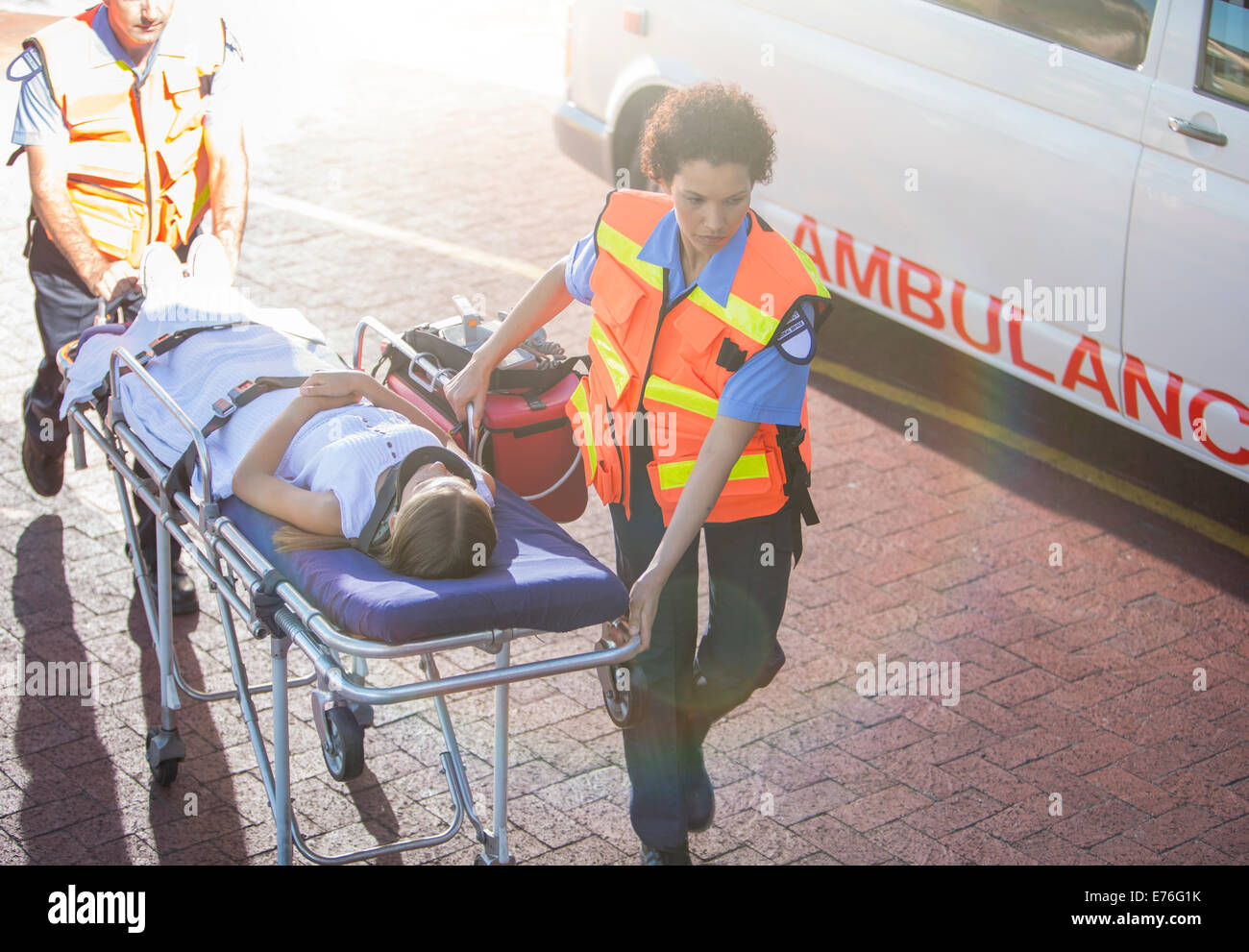 Paramedics wheeling patient in hospital parking lot Stock Photo