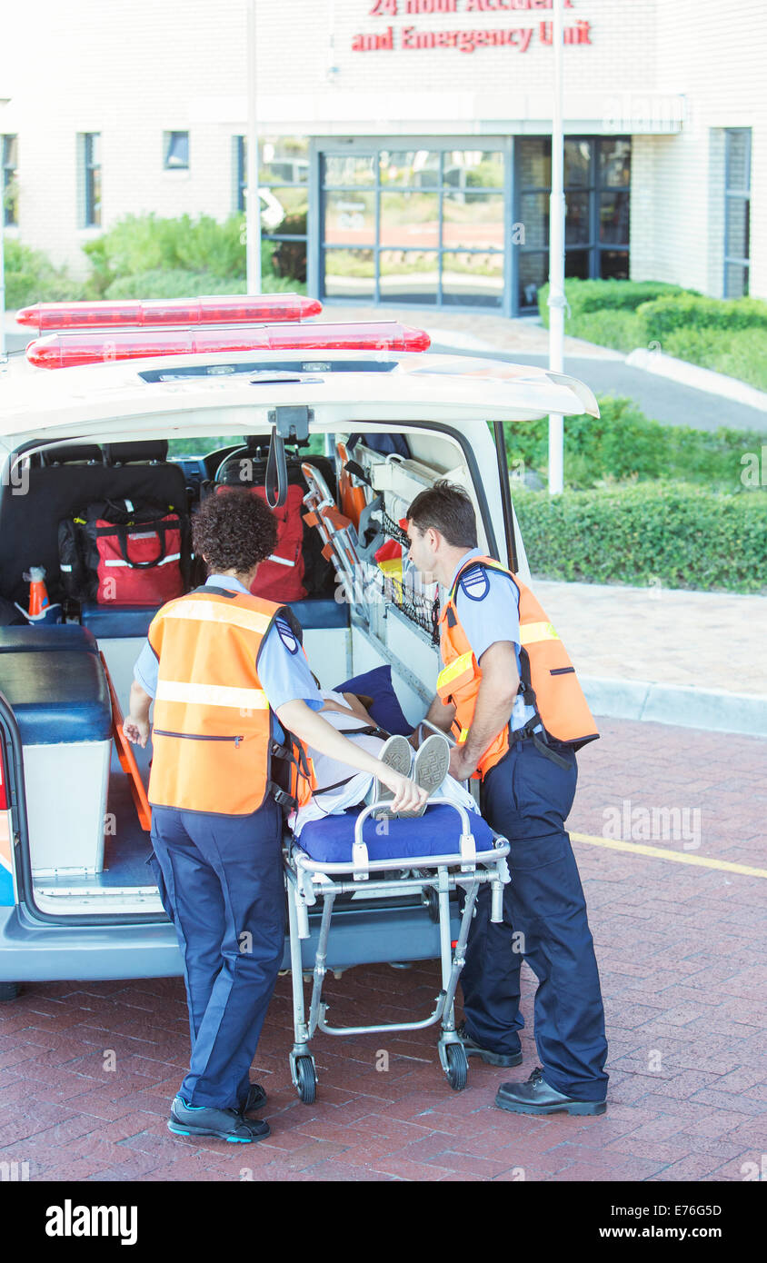 Paramedics wheeling patient out of ambulance Stock Photo
