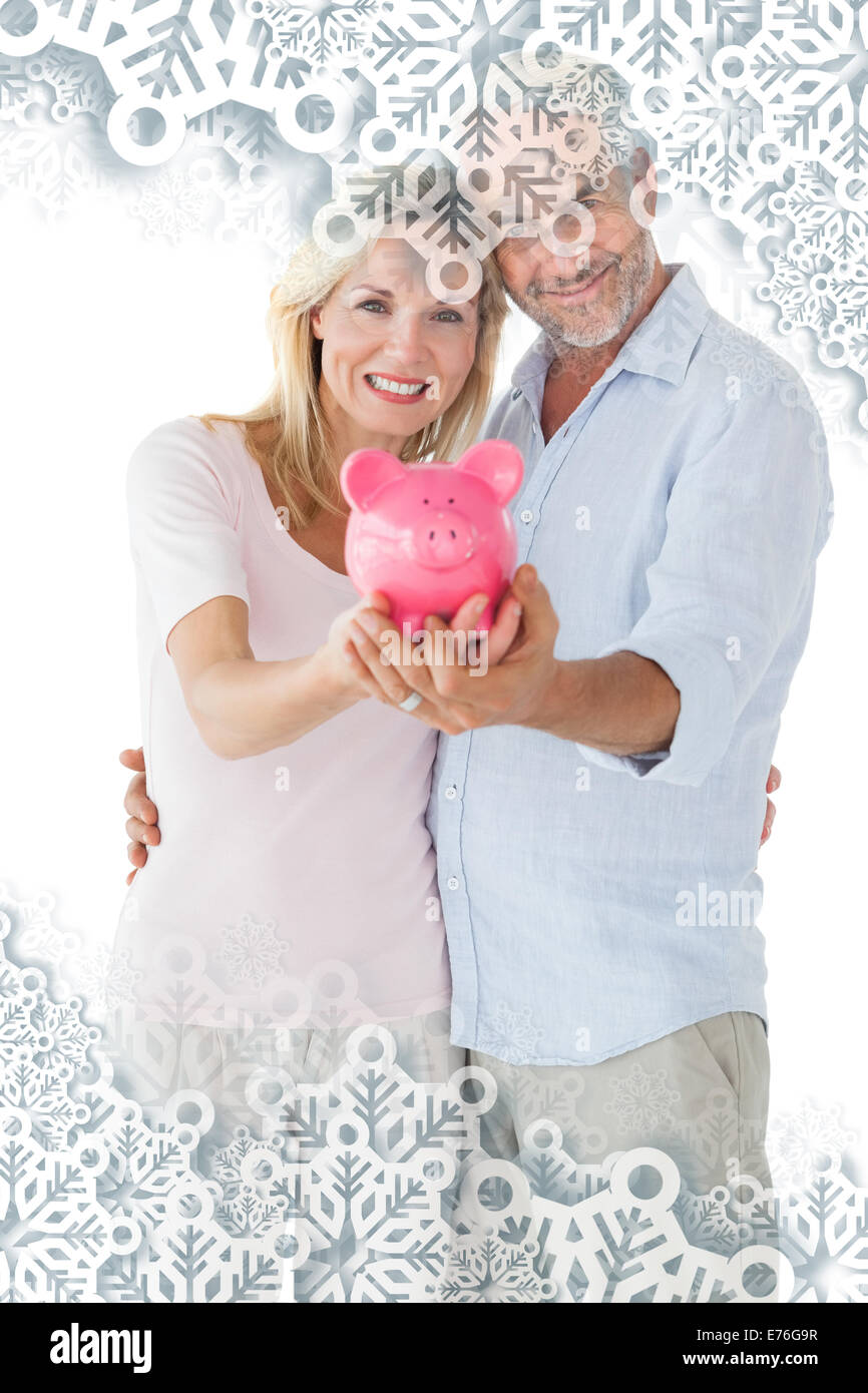 Composite image of happy couple showing their piggy bank Stock Photo ...